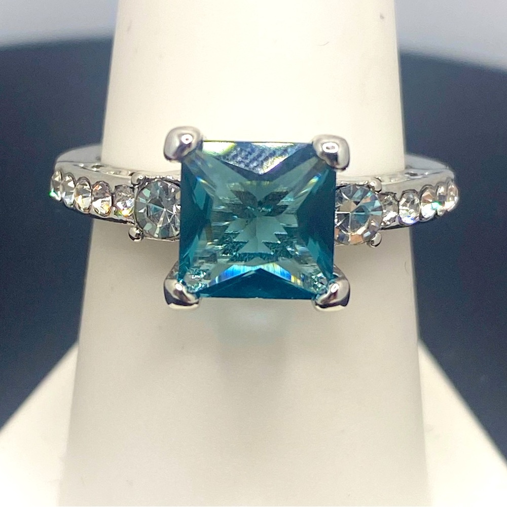 This silver tone Swiss blue topaz color princess cut stone with crystals on side